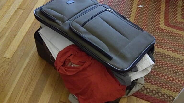 Open suitcase being packed with folded clothes for a trip